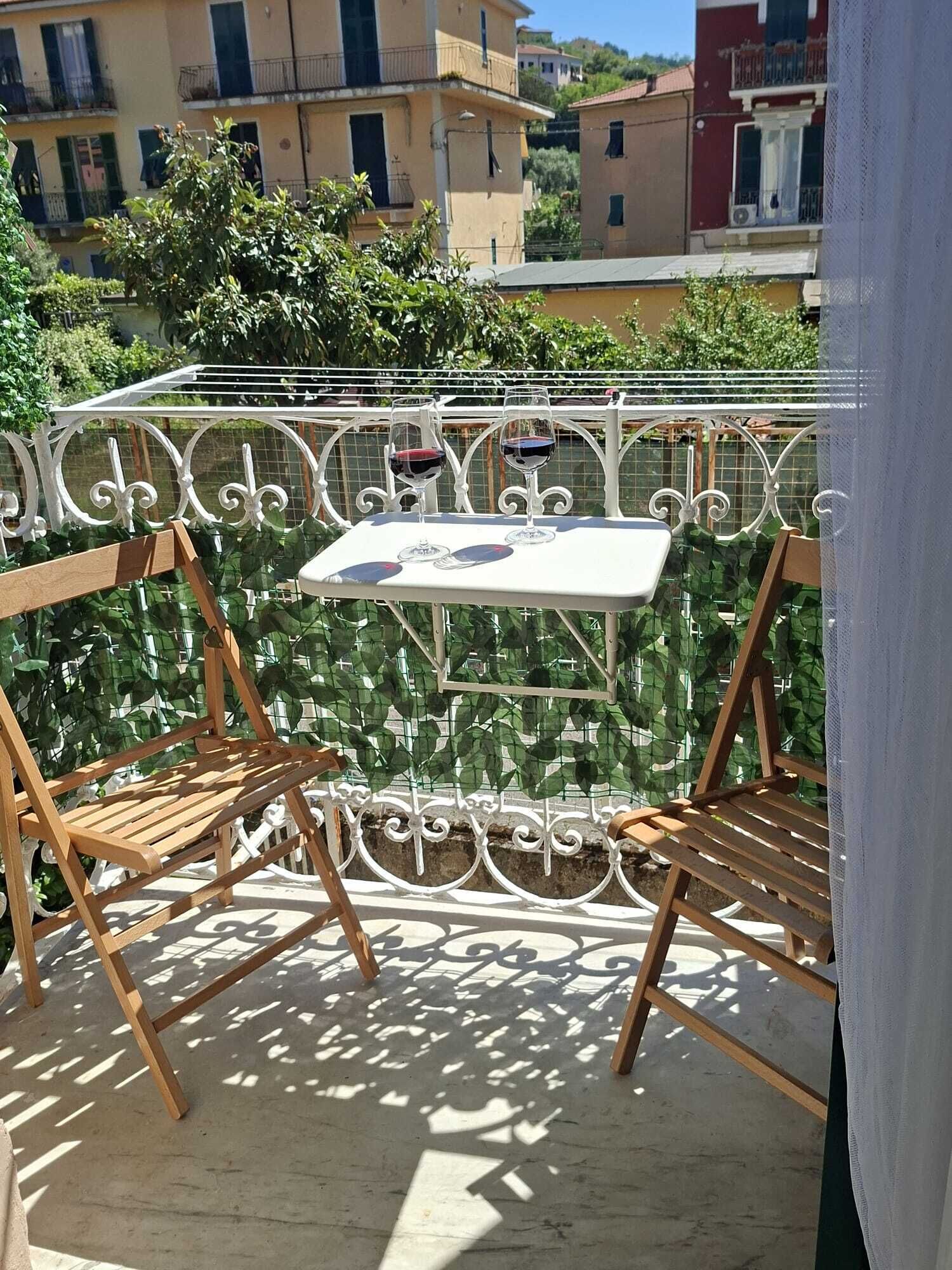 Un balcon avec une table et deux chaises, entouré d’une rambarde en métal.