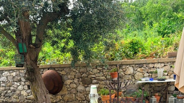 A table with a woven basket of lemons and a metal stand with a bottle. - Arola Rustic Retreat (Arola-Preazzano)