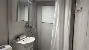 Ett badrum med ett vitt handfat, en spegel, en dusch och en duschdraperi.