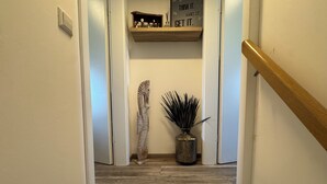 Eine Holztreppe mit Handlauf, einer dekorativen Skulptur eines Meerestitanes, einem Blumentopf und einem motivierenden Spruch auf einem Regal.