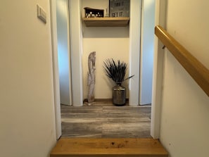 A wooden staircase with a handrail, a decorative seahorse sculpture, a potted plant, and a motivational sign on a shelf. - Het Baken 163, a quiet resort near Lake Grevelingen and the North Sea (Scharendijke)