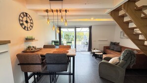 Ein modernes Interieur mit Essbereich, einer Couch, einer Treppe und Blick durch eine Glastür.
