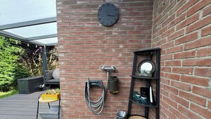 Eine Backsteinwand, eine Uhr, ein Regal mit Dekoration und Sitzgelegenheiten im Freien.