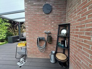 A brick wall with a clock, a shelf with decorative items, and outdoor seating. - Het Baken 163, a quiet resort near Lake Grevelingen and the North Sea (Scharendijke)