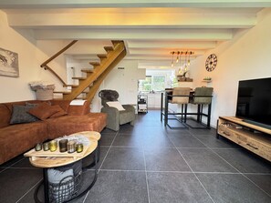 A modern living room with a sofa, a coffee table, a TV, and a staircase leading to an upper level. - Het Baken 163, a quiet resort near Lake Grevelingen and the North Sea (Scharendijke)