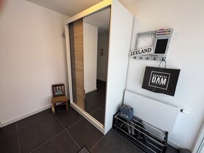 A modern interior with a sliding door leading to a hallway, a small wooden stool, a wall-mounted rack with bags, and a sign that reads 'ZEELAND.' - Het Baken 163, a quiet resort near Lake Grevelingen and the North Sea (Scharendijke)