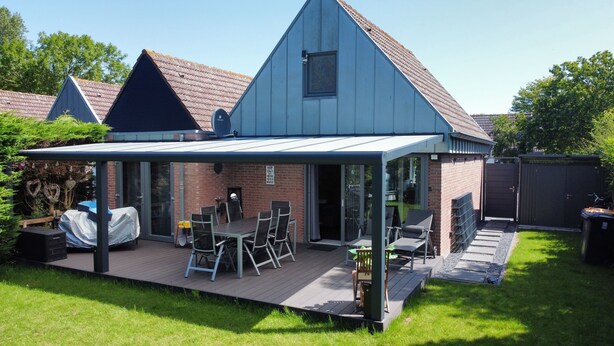 Ein Haus mit überdachter Terrasse, Ziegelaußenwand und kleiner Holzterrasse.