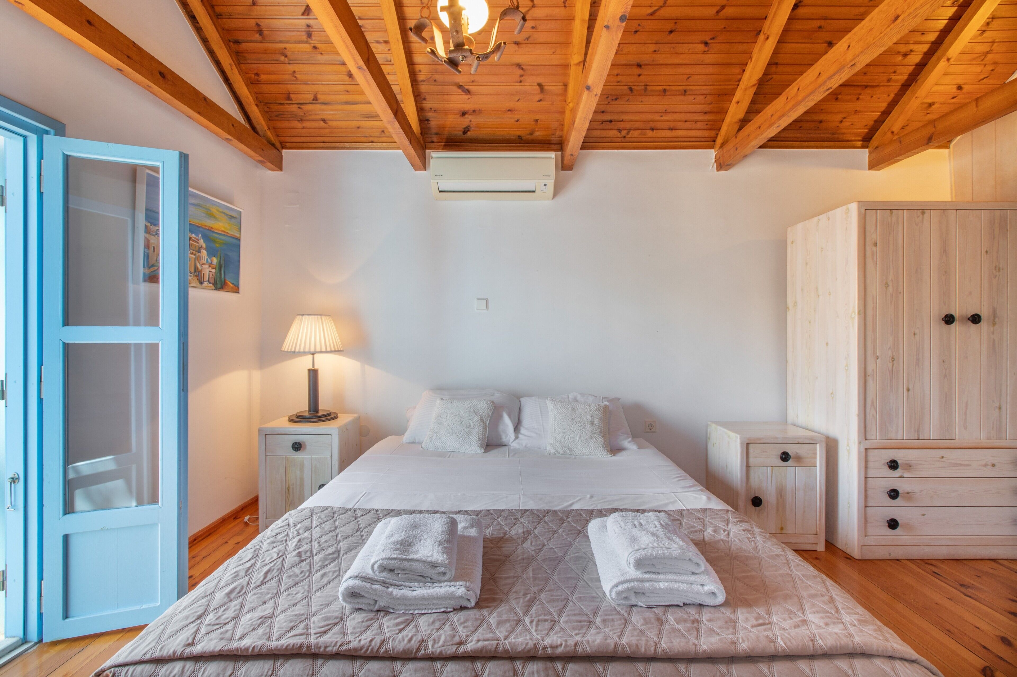 A bedroom with a bed, nightstands, a lamp, a wardrobe, and a door.