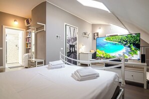 Een hotelkamer met een bed, een televisie, een bureau, een boekenplank en een douche.