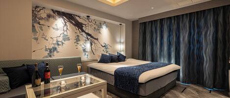 Una habitación de hotel moderna con una cama, una mesa de centro de vidrio, un sofá y una pared con un mural decorativo.