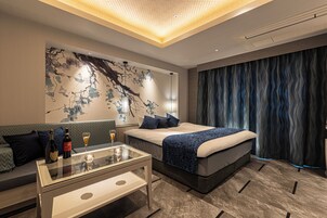 Una habitación de hotel moderna con una cama, una mesa de centro de vidrio, un sofá y una pared con un mural decorativo.