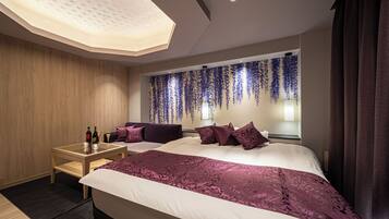 A modern hotel room with a large bed, a small table with drinks, and a decorative wall.