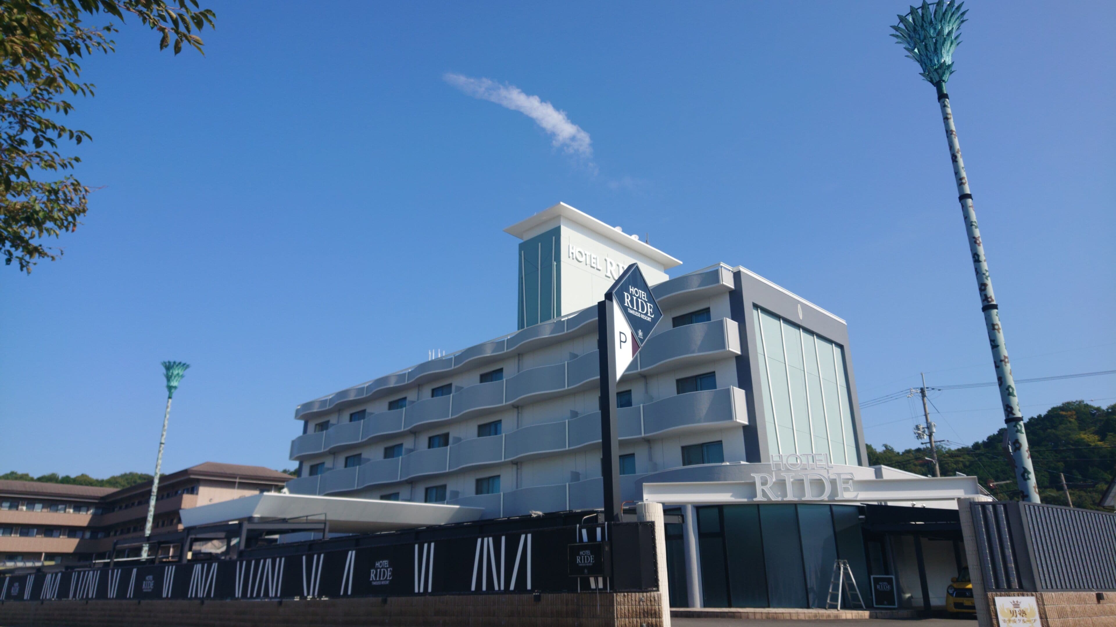 A multi-story hotel with a prominent 'Hotel Ride' sign, a modern architectural design, and a clear blue sky.