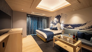 A modern hotel room with a bed, a desk, a sofa, and a dining table.