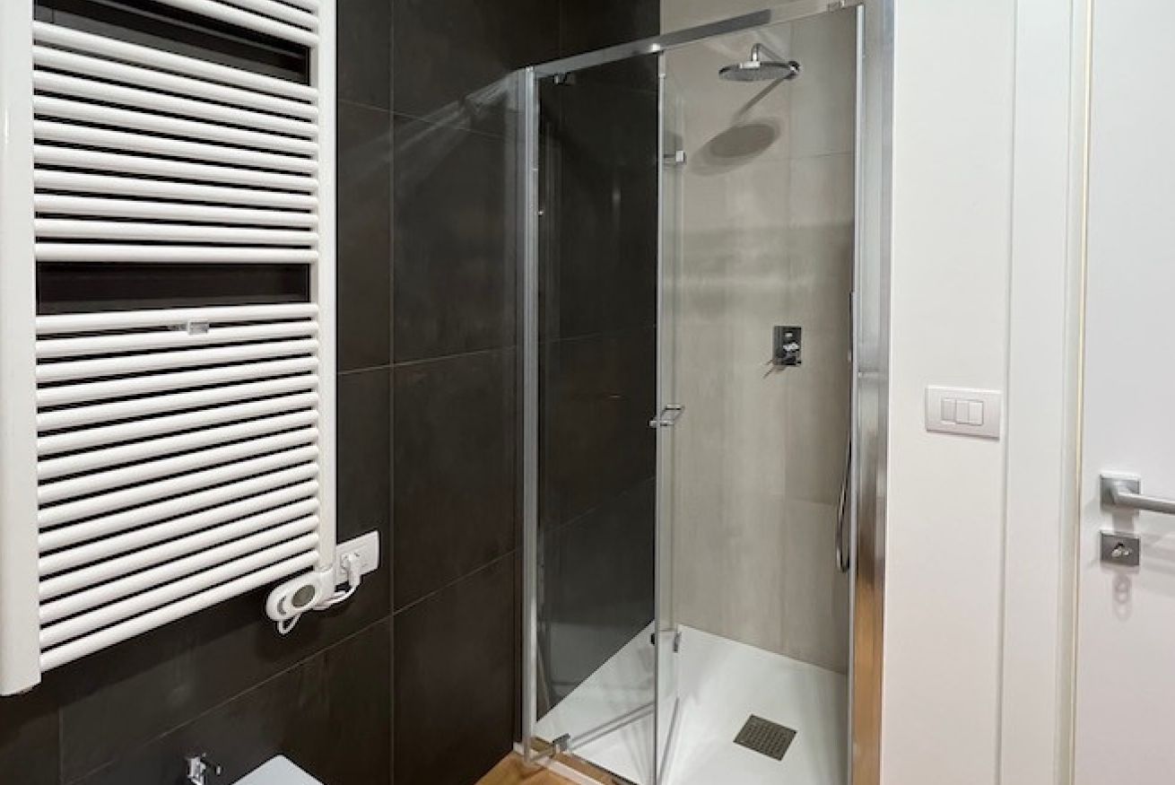 Ein modernes Badezimmer mit Duschkabine aus Glas, einem weißen Handtuchhalter und einem Waschbecken.