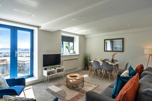 Ein modernes Wohnzimmer mit großem Fenster, Essbereich und Fernseher.