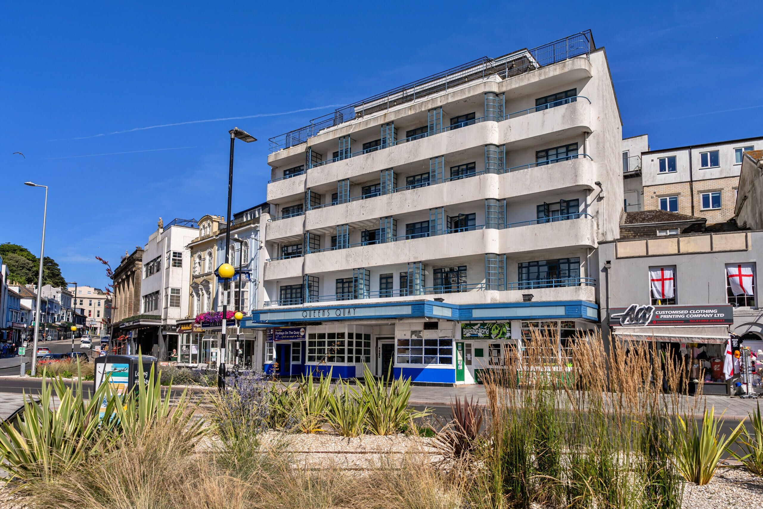 Ein mehrstöckiges Gebäude mit flacher Fassade, Balkonen und einem Eingang im Erdgeschoss.