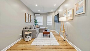 A living room with a sofa, coffee table, and a TV on a stand. - Modern 5BR House with AC in Central Berkeley (Berkeley)