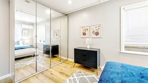 A bedroom with a bed, a dresser, a mirror, and a window. - Modern 5BR House with AC in Central Berkeley (Berkeley)