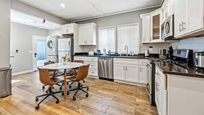 A modern kitchen with white cabinets, stainless steel appliances, and a dining area with a table and chairs. - Modern 5BR House with AC in Central Berkeley (Berkeley)