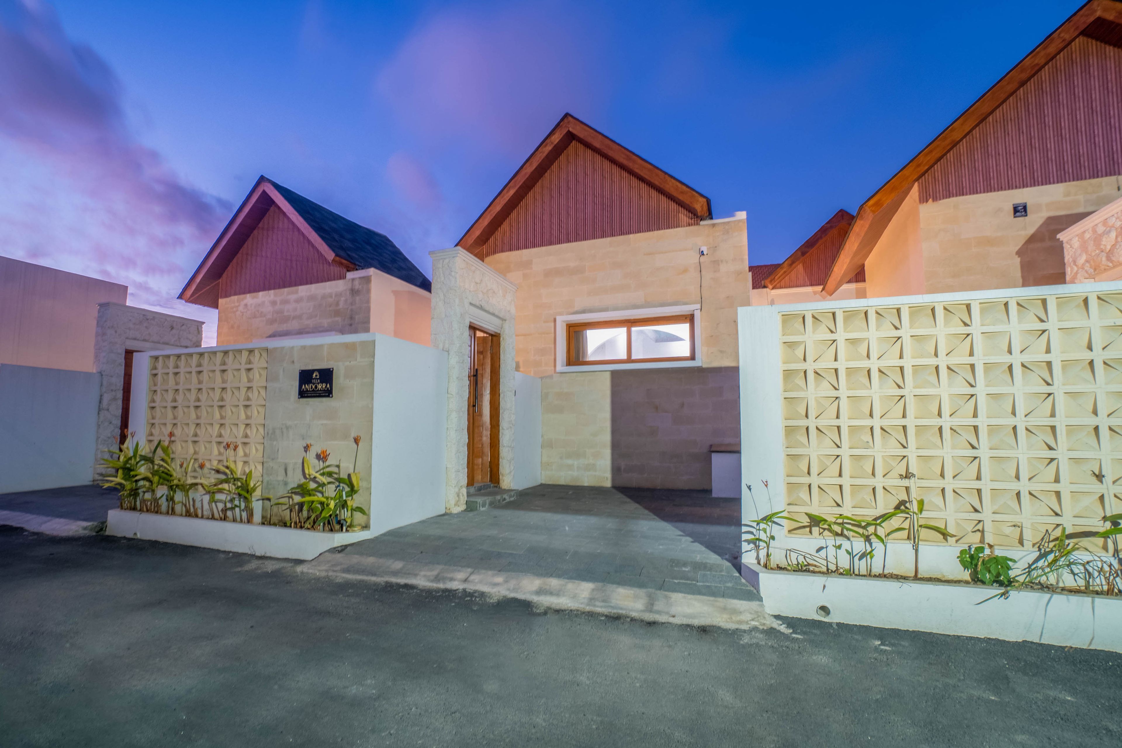A modern building with a stone facade, a wooden entrance, and a gated driveway.