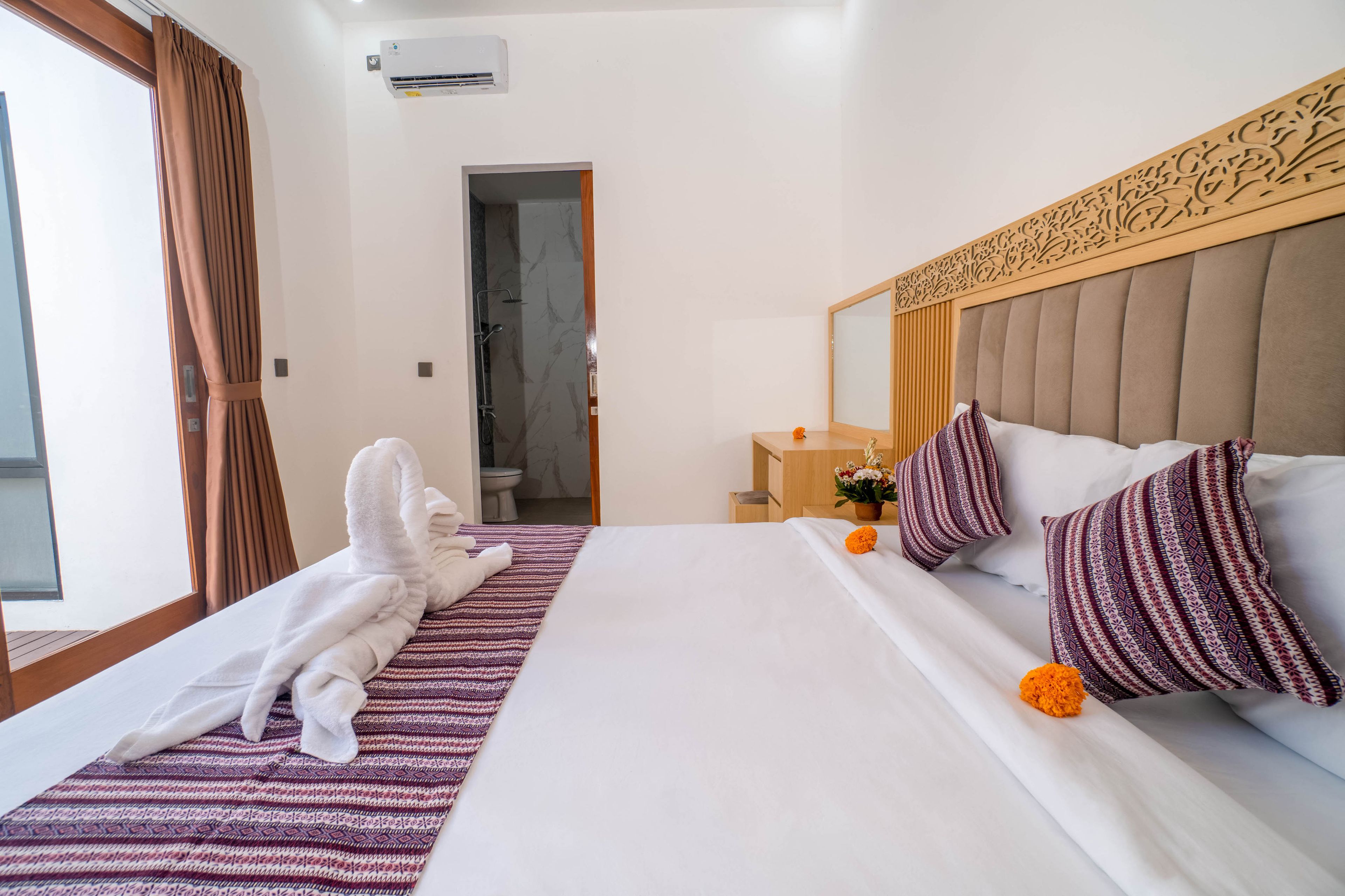 A hotel room with a bed, a bathroom, and a view of the outside.