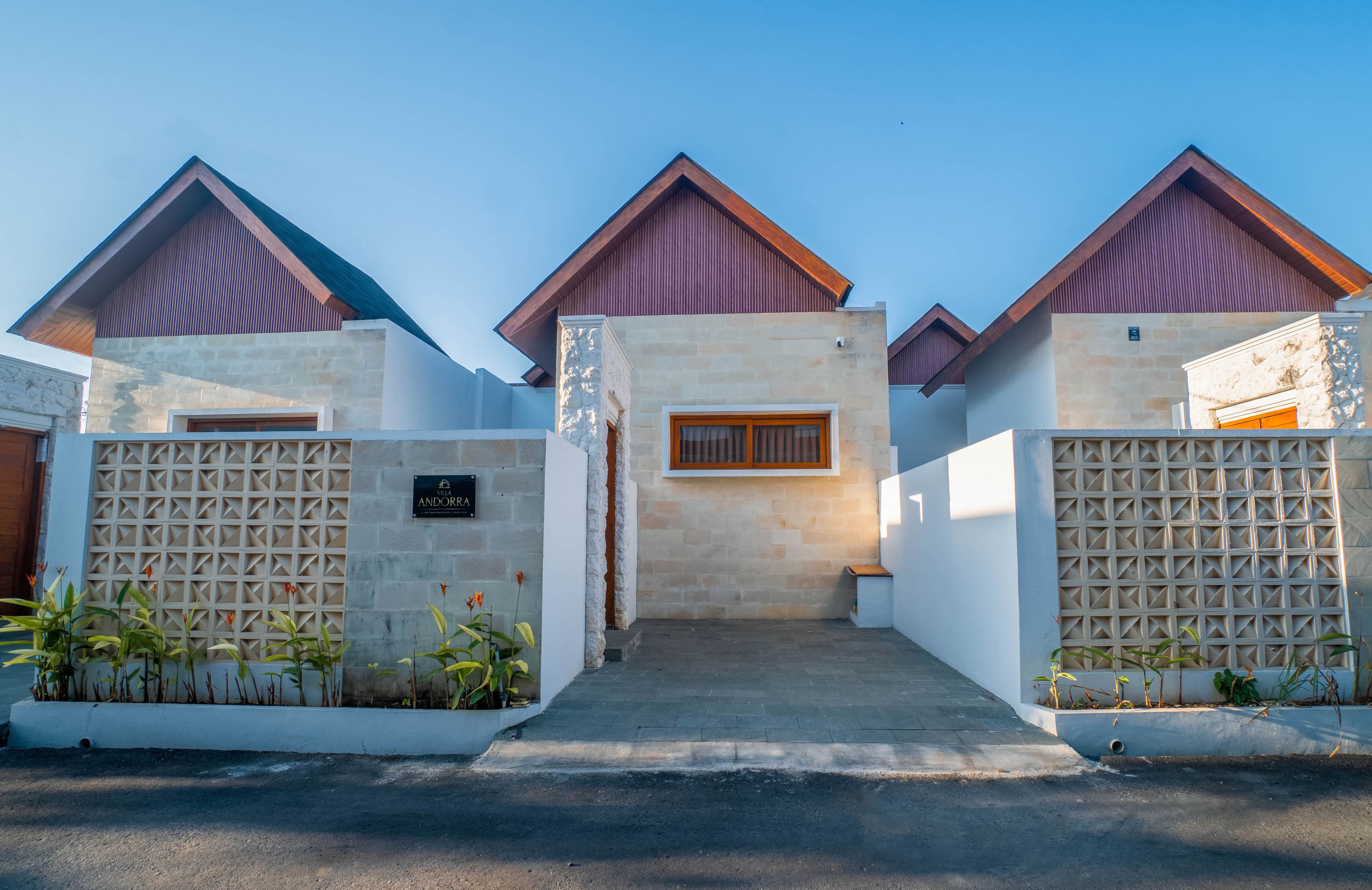 A modern villa with a stone facade, a wooden door, and a gated entrance.