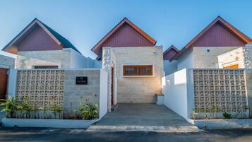 A modern villa with a stone facade, a wooden door, and a gated entrance.
