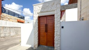 Ein Haus mit einer Stein-Fassade, einer Holztür und einer Betonmauer.