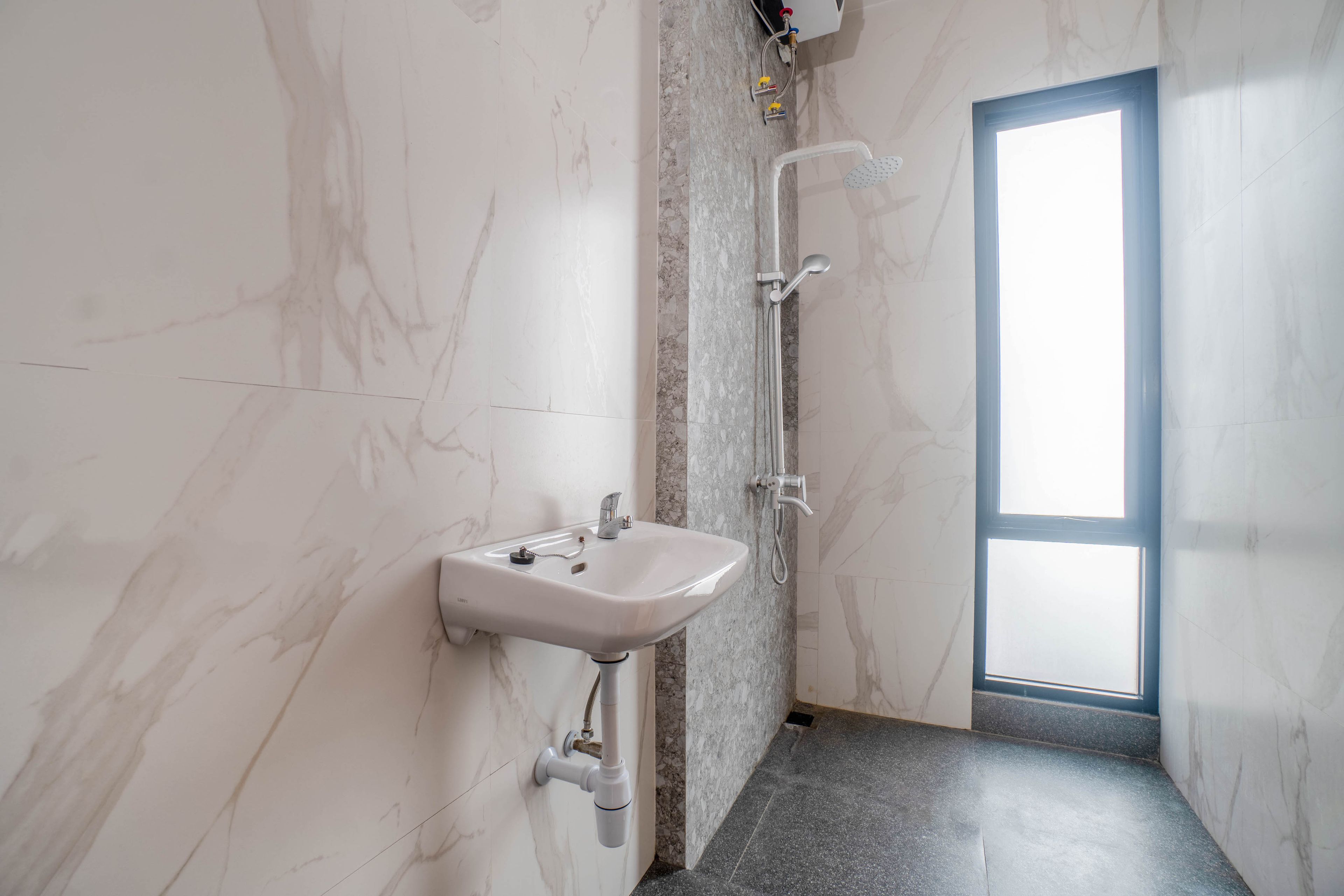A bathroom with a marble wall, a sink, and a shower.