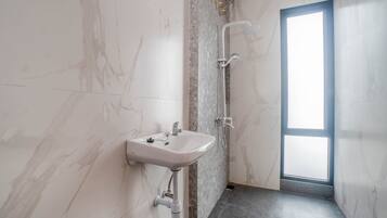 A bathroom with a marble wall, a sink, and a shower.