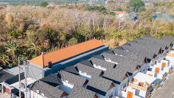 A residential area with multiple houses, a prominent red-roofed building, and a clear view of the ocean.