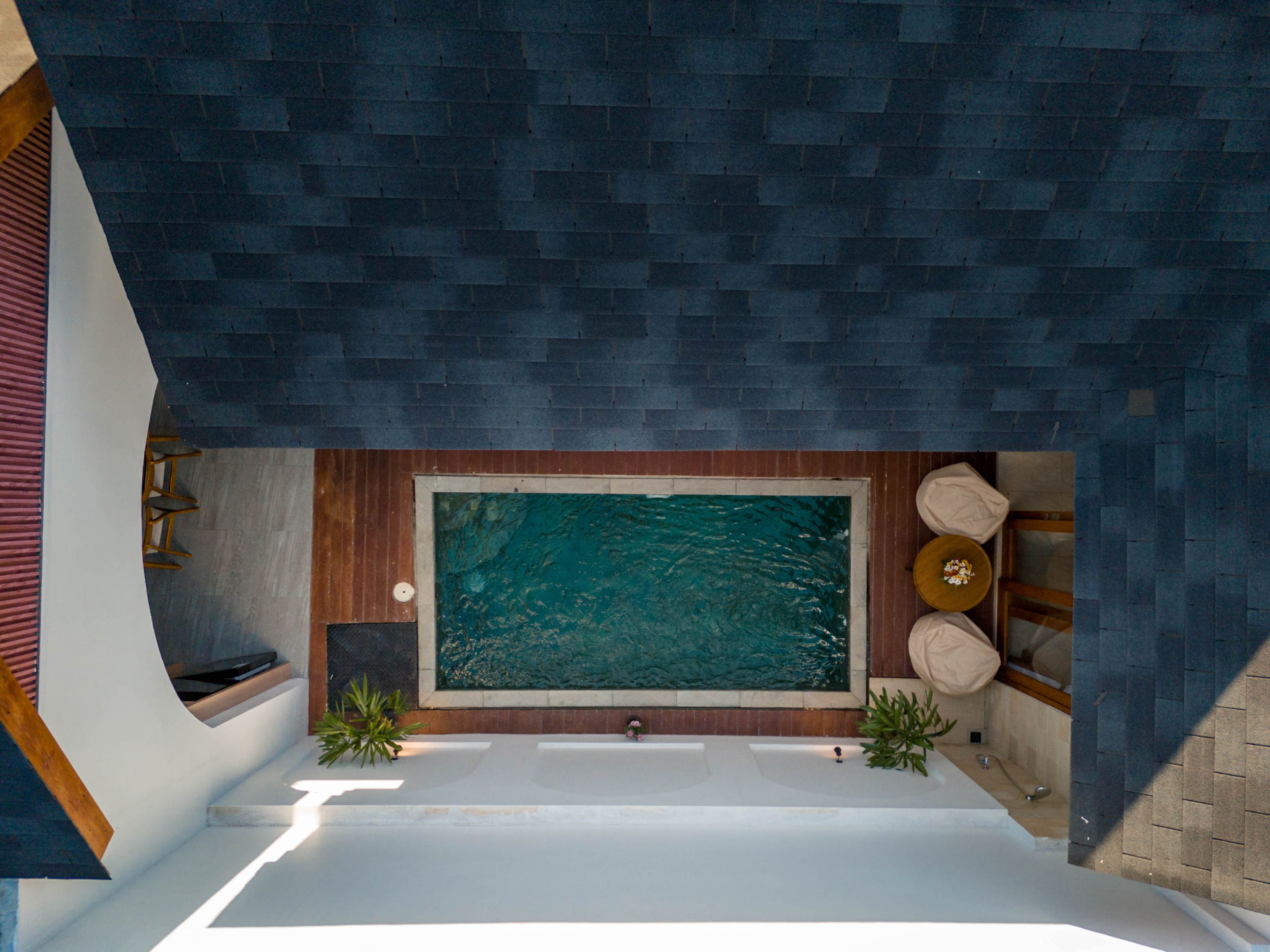 Een moderne badkamer met een groot bad, een wand van houten panelen en een zithoek met kussens.