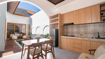 A modern kitchen with wooden cabinets, a tiled backsplash, and a dining area with a pool view.