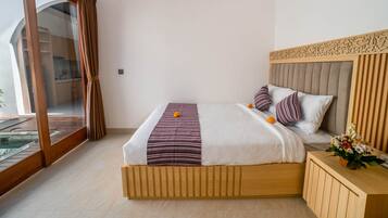 A hotel room with a large bed, wooden headboard, and a view of a pool through a sliding glass door.