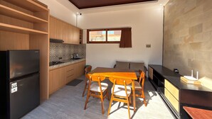 Eine moderne Küche mit Holzschränken, einem schwarzen Kühlschrank, einem Esstisch mit Stühlen und einer Steinwand.