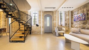 A modern interior with a spiral staircase, stone walls, a gray door, and a white sofa. - Unique Luxury 3BR Duplex on HaNeviim-Private Pool and Free Parking (Jerusalem)