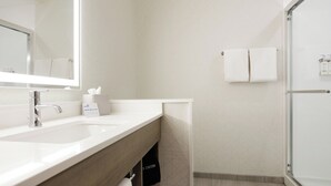 A modern bathroom with a large mirror, a sink, a towel rack, and a shower area. - Holiday Inn Express Knoxville Airport Alcoa by IHG (Alcoa)