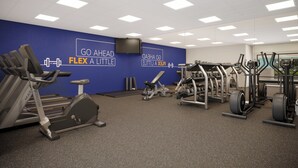 A gym with various exercise equipment, a blue wall with motivational text, and a ceiling with square lights. - Holiday Inn Express Knoxville Airport Alcoa by IHG (Alcoa)