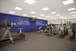 A gym with various exercise equipment, a blue wall with motivational text, and a ceiling with square lights. - Holiday Inn Express Knoxville Airport Alcoa by IHG (Alcoa)