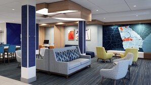 A modern hotel lobby with a sofa, chairs, a desk, and a large map on the wall. - Holiday Inn Express Knoxville Airport Alcoa by IHG (Alcoa)