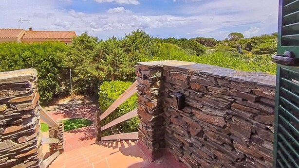 A stone wall, a staircase, and a view of greenery and a building in the distance. - Between Sea & Nature – 3 Minutes from La Pelosa (Stintino)