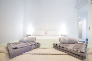A hotel room with a bed, two bedside tables, and a view of a hallway. - Themis Apartment (Kalamata)