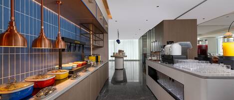 Una cocina moderna con una encimera larga, varios recipientes de comida y una estación de café.