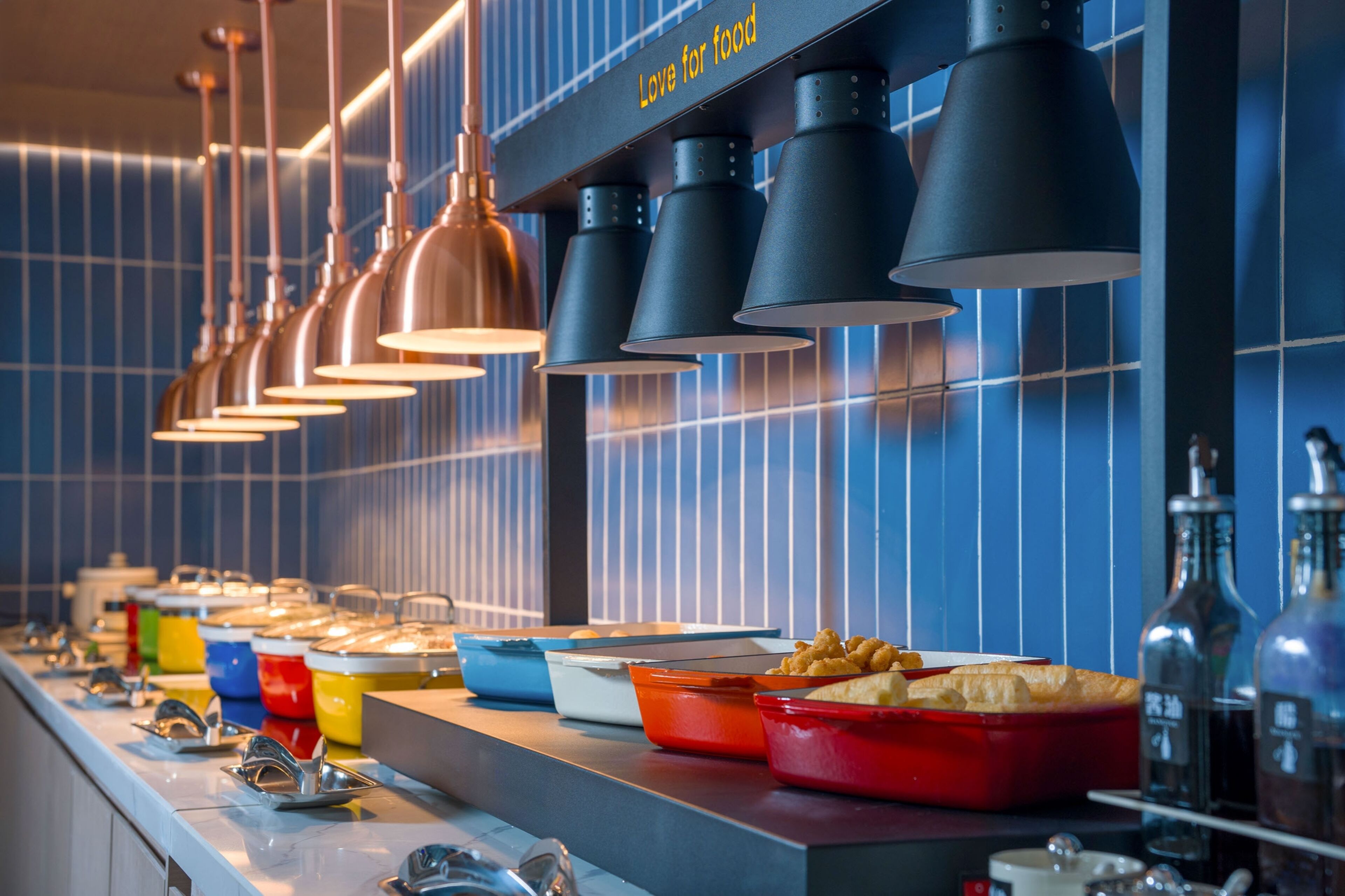 A buffet setup with various food containers and a row of hanging lights.