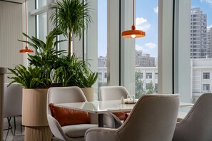 A modern dining area with a table, chairs, and potted plants.