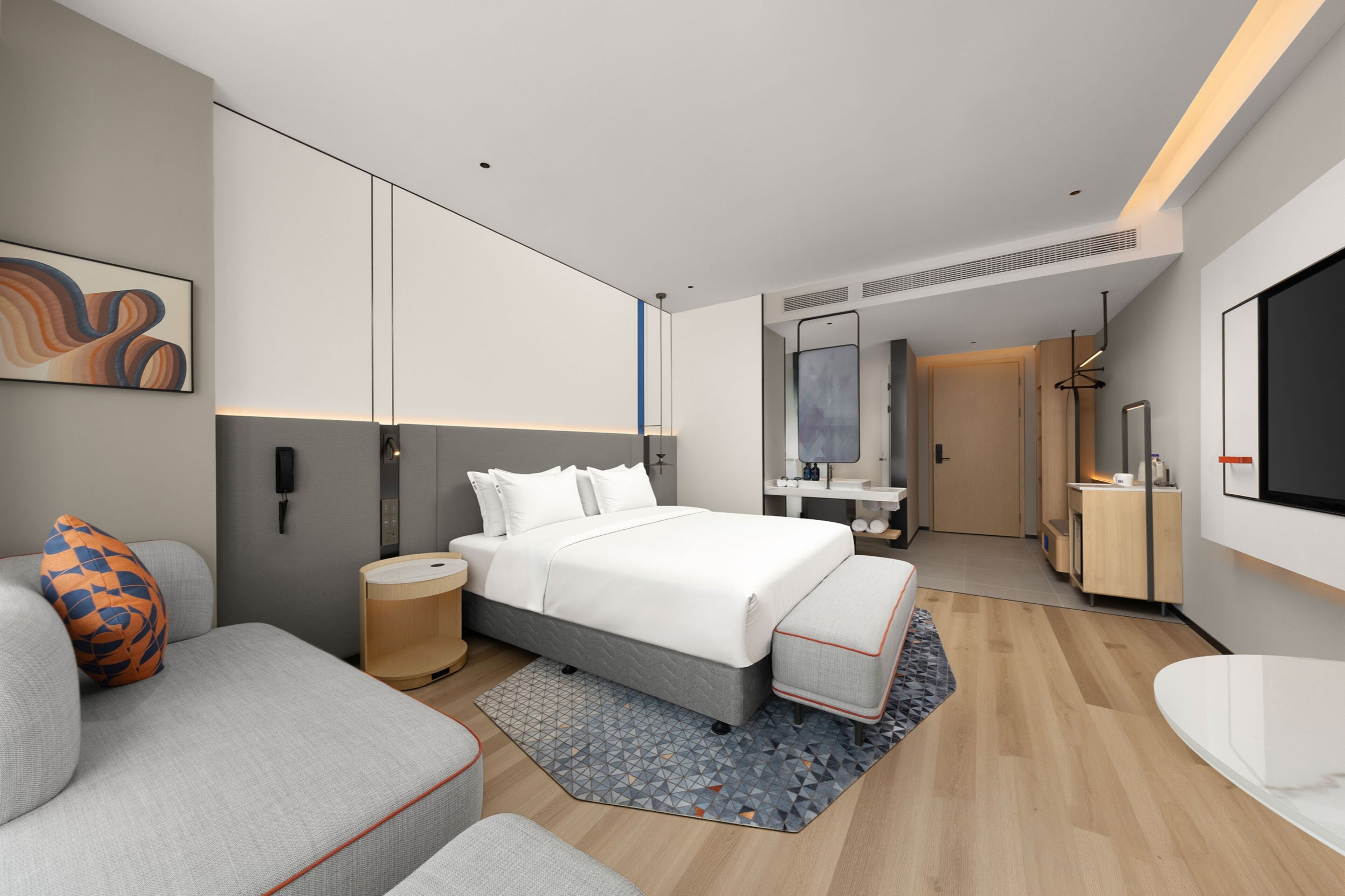 Een moderne hotelkamer met een groot bed, een bank, een bureau en een badkamer.