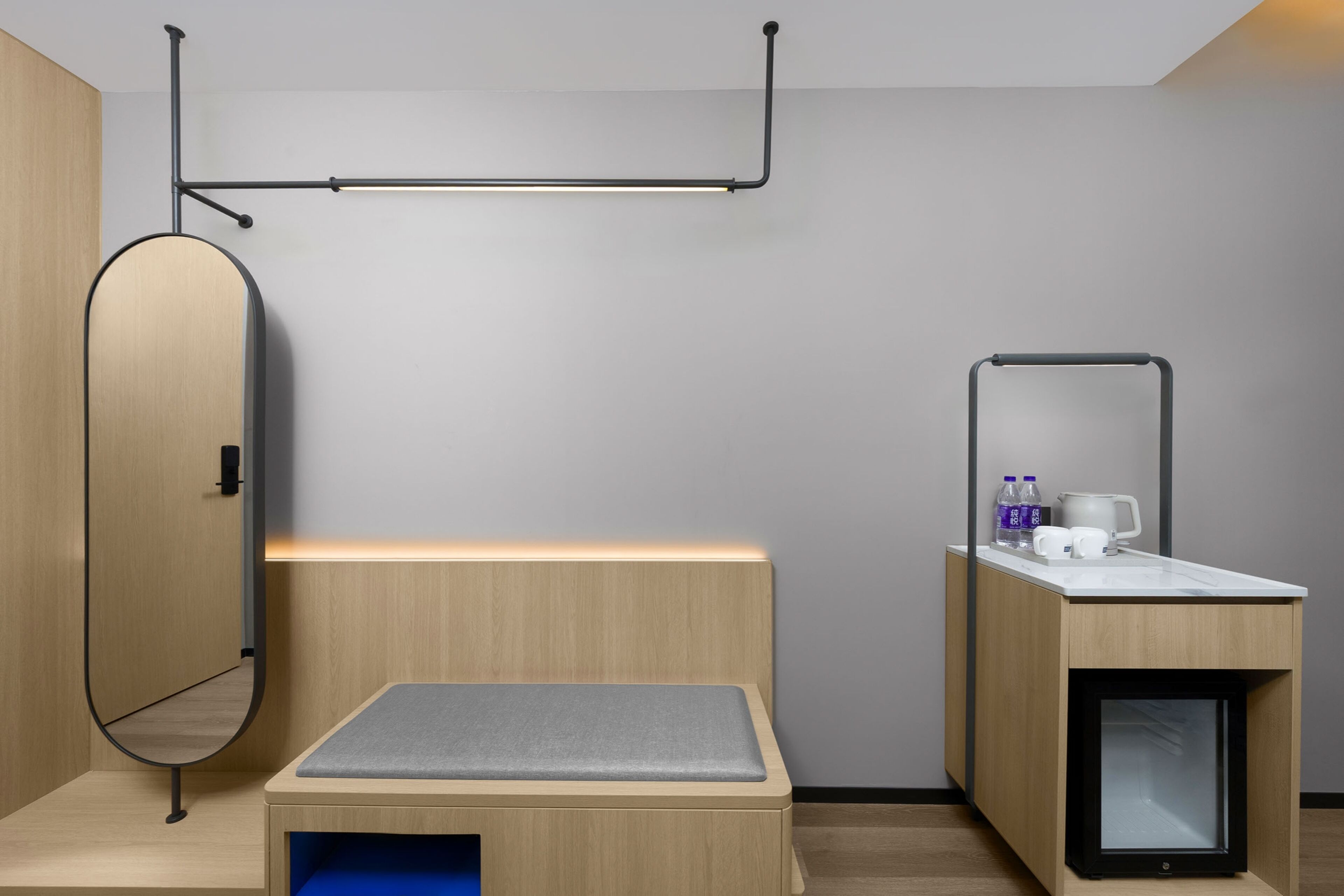 Una habitación moderna y minimalista con cama, un pequeño escritorio, un espejo y un armario empotrado.