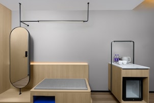 Una habitación moderna y minimalista con cama, un pequeño escritorio, un espejo y un armario empotrado.