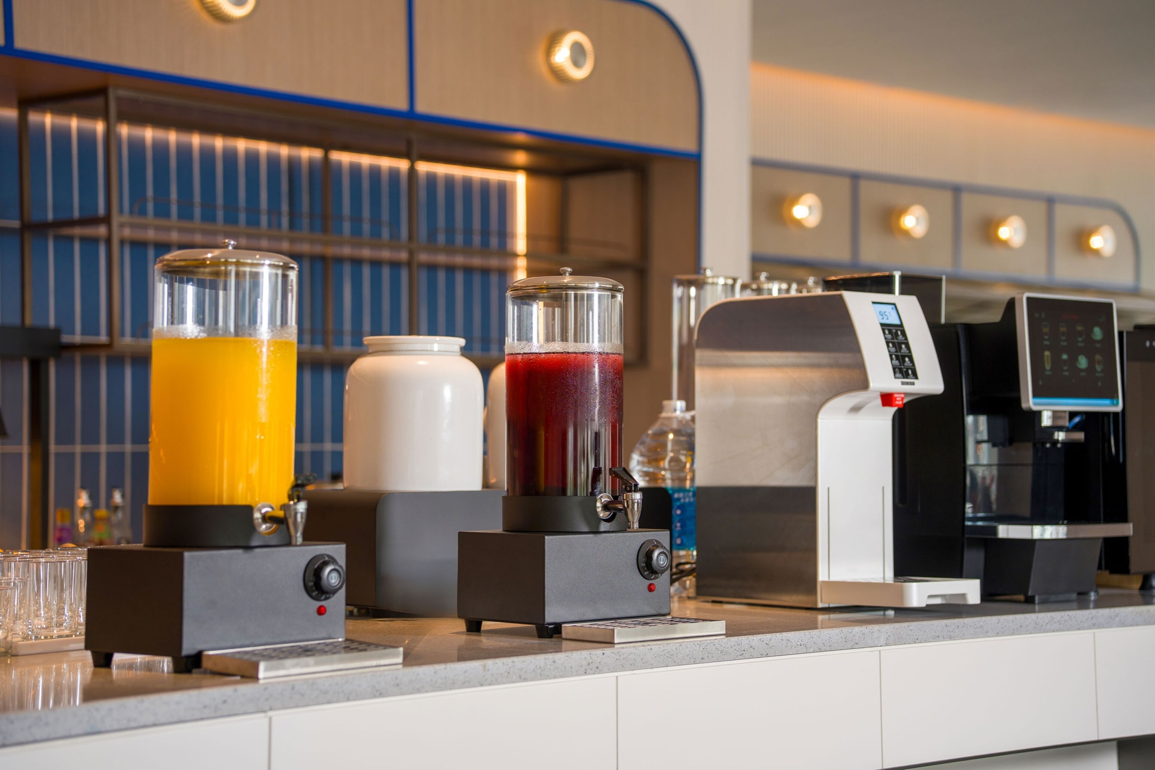 A coffee machine and two beverage dispensers on a counter.